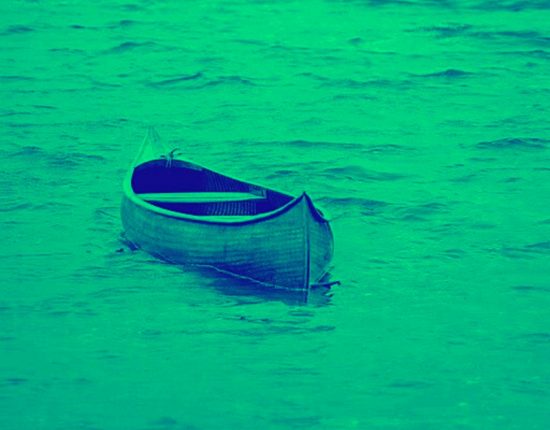 green-filtered image of empty canoe floating on water