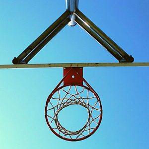 image of basketball hoop from below, silhouetted against a blue sky